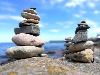 Stack of pebbles in sea against sky