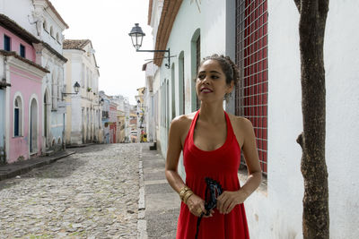 Portrait of a woman wearing red dress on a street. 
