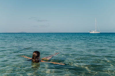 Rear view of woman swimming in sea against sky