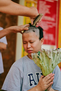 Cropped hands of barber cutting young man hair