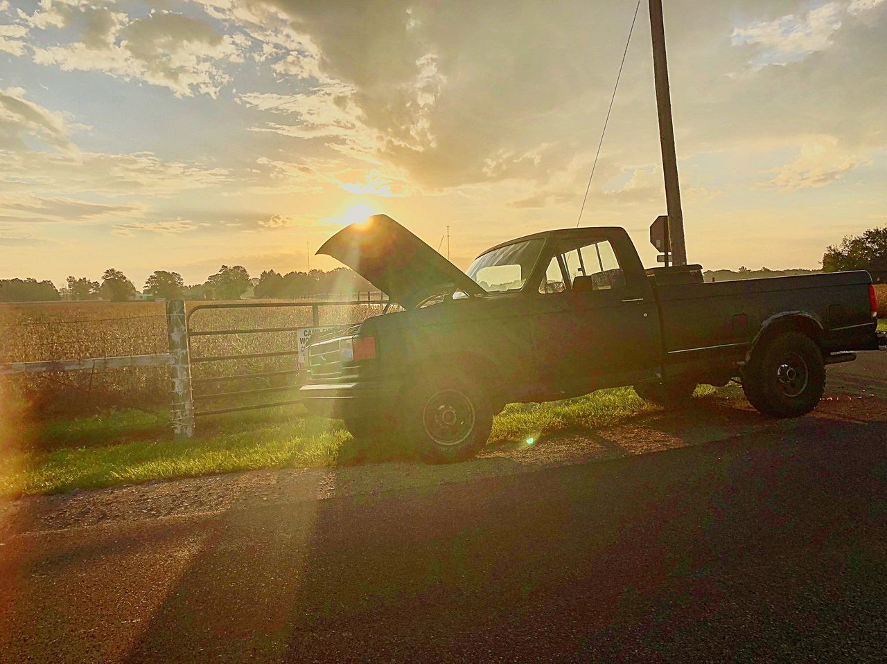 ROAD AMIDST FIELD AGAINST SKY AT SUNSET