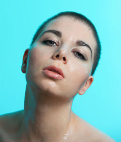 Close-up portrait of shirtless wet woman against wall