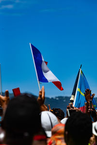 Rear view of people by flags against clear blue sky