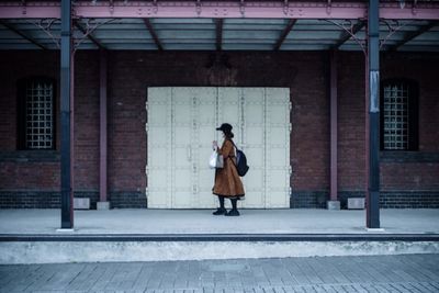 Full length of woman standing against building