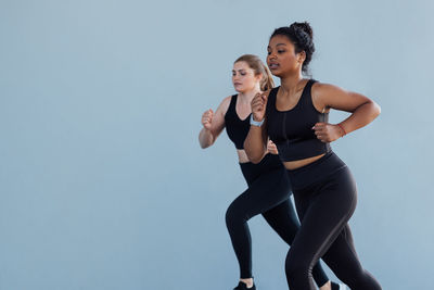 Low angle view of young woman exercising against wall