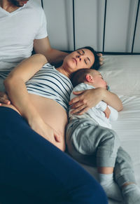 Close-up of man and woman with baby on bed at home