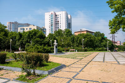 Trees by footpath against buildings in city