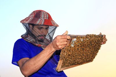 Honey farming - honey farmer standing with bee box working with bees 