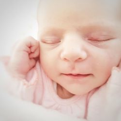 Close-up of baby girl sleeping against white background