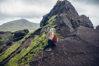 Rear view of woman on rock against sky