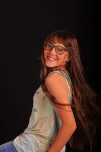 Portrait of smiling young woman against black background