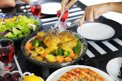 Cropped hands of woman eating meat on dining table