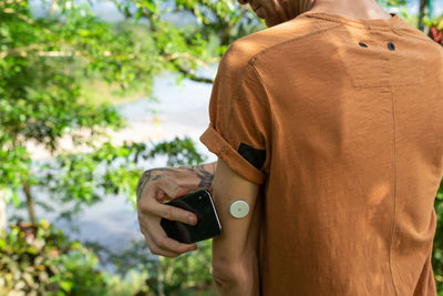 Rear view of woman holding camera outdoors