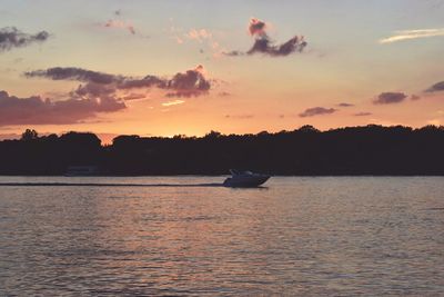 Silhouette boat sailing in sea against sky during sunset