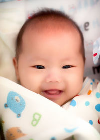 Portrait of cute baby girl lying on bed