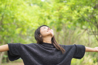 Young woman looking away against trees