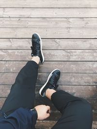 Low section of man sitting on boardwalk