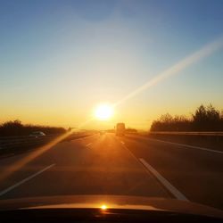 Road against sky during sunset seen through car windshield