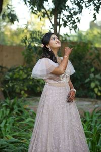 Young woman wearing dress standing against plants