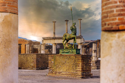 Statue on wall of building against sky