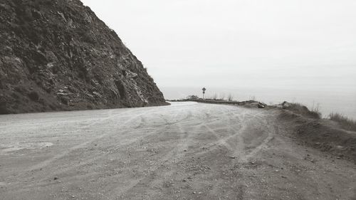 Scenic view of road by sea against clear sky