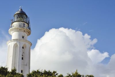 Low angle view of lighthouse by building against sky