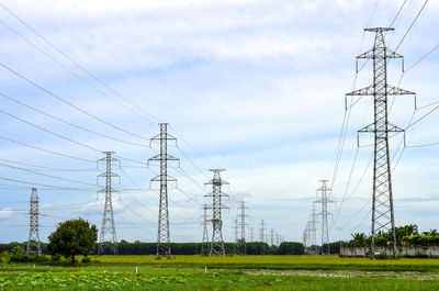 Electricity pylon on field against sky