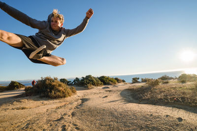 Low angle view of man jumping against sky