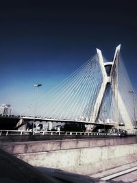 Low angle view of suspension bridge against clear blue sky