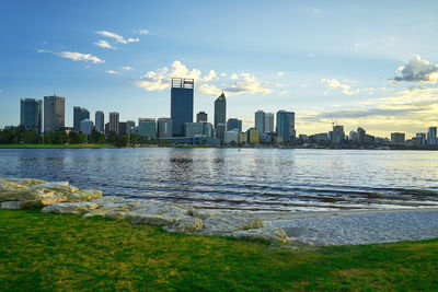 City at waterfront against cloudy sky
