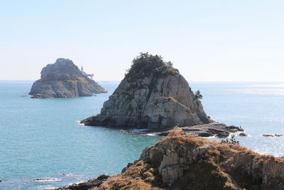 Rock formations by sea against clear sky