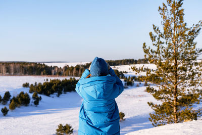 Rear view of woman standing on snow covered landscape