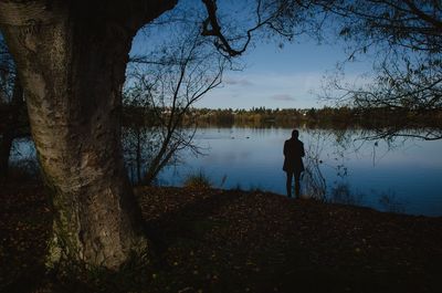 Rear view of silhouette man by lake against sky