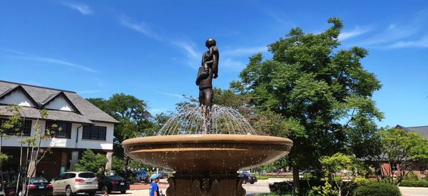 Statue by fountain against sky