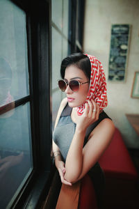 Woman wearing sunglasses sitting on window