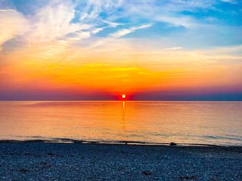 Scenic view of sea against dramatic sky during sunset