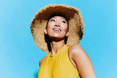 Portrait of young woman wearing hat against clear blue sky