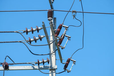 Low angle view of electricity transformer against clear blue sky