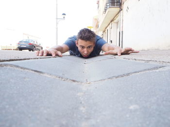 Surprised man lying down on street in city