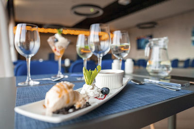 Various dessert arranged in plate by wineglasses on table at restaurant