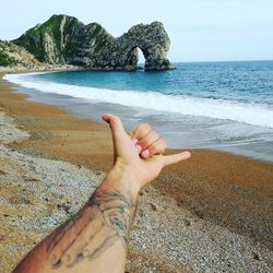 Low section of person on beach against sky