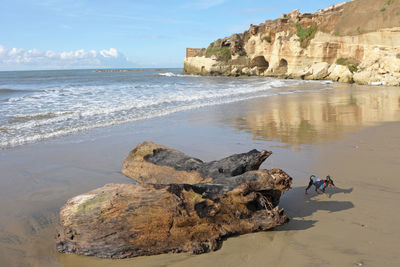 Rocks on shore by sea against sky