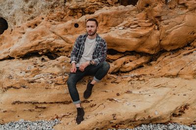 Full length portrait of young man standing on rock