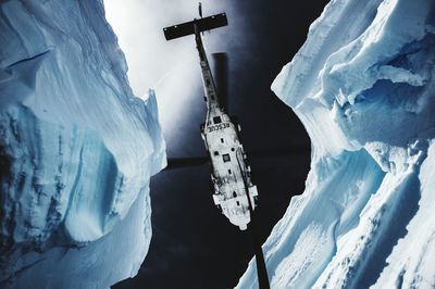 Directly below of helicopter amidst snowcapped mountains on sunny day