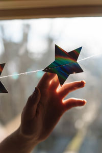 Cropped hand touching star shape on window