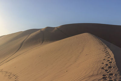 Sand dunes in desert against clear sky