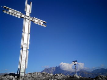 Low angle view of road sign against clear blue sky