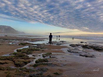 Man standing on beach against sky during sunset