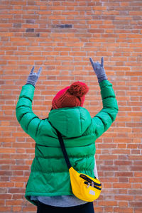 Rear view of man standing against brick wall