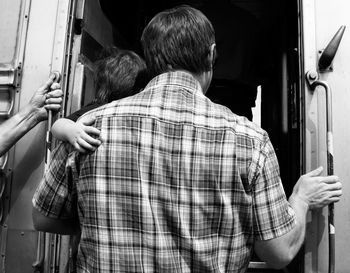 Rear view of man standing at train door